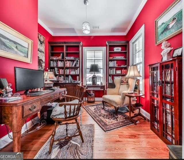 home office with visible vents, crown molding, and wood finished floors