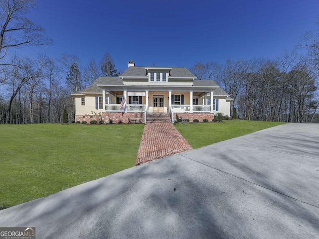 view of front of home with roof with shingles, a porch, a front lawn, and a chimney