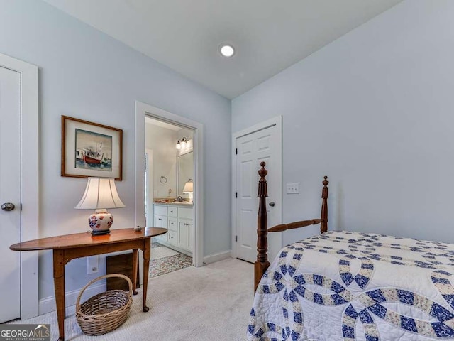 bedroom featuring baseboards, ensuite bathroom, and light colored carpet