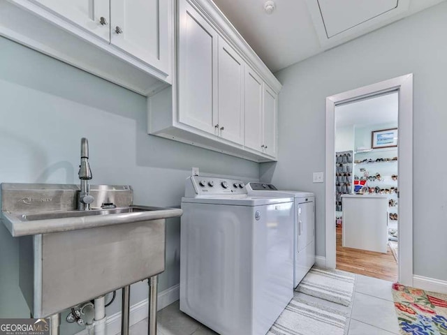 washroom with light tile patterned floors, a sink, baseboards, cabinet space, and washer and clothes dryer