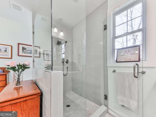 bathroom with a shower stall and visible vents