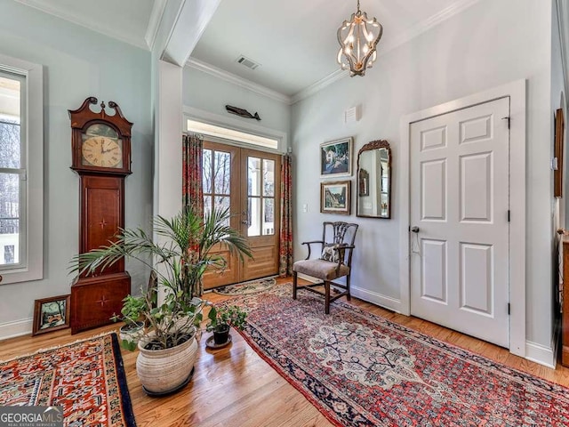 foyer with ornamental molding, wood finished floors, visible vents, and baseboards