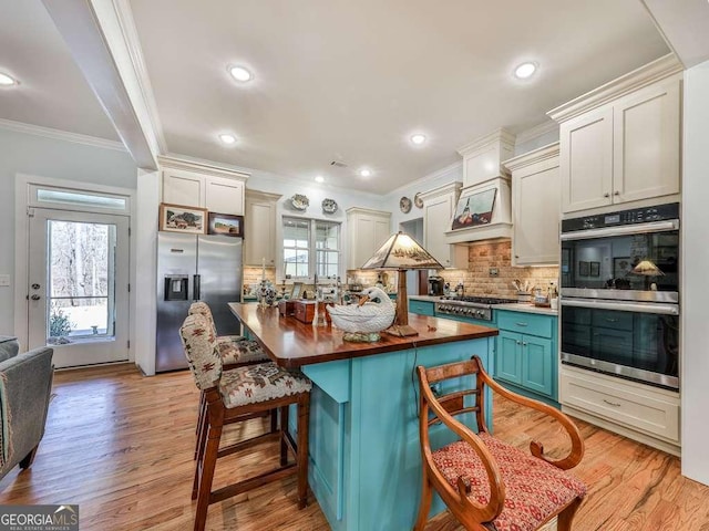 kitchen featuring custom exhaust hood, light wood finished floors, appliances with stainless steel finishes, and a wealth of natural light