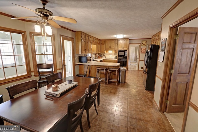 dining room with ceiling fan, ornamental molding, and a textured ceiling