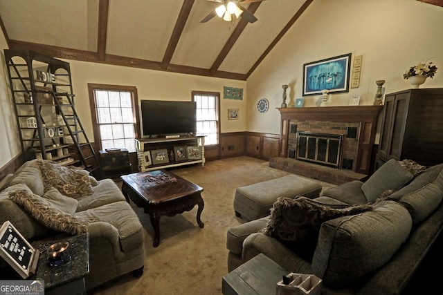 carpeted living room featuring a wainscoted wall, high vaulted ceiling, a brick fireplace, and beam ceiling