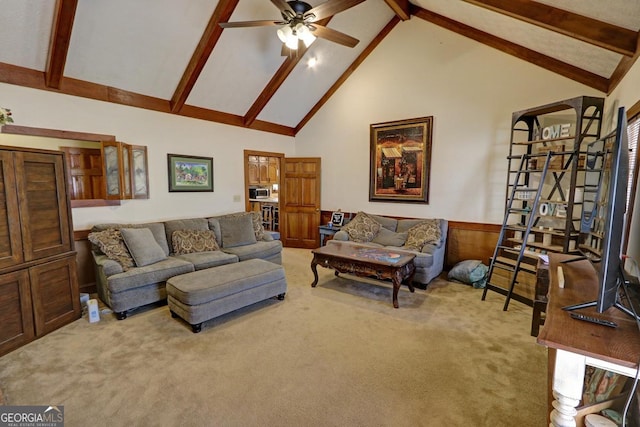 carpeted living room featuring ceiling fan, high vaulted ceiling, a wainscoted wall, and beam ceiling