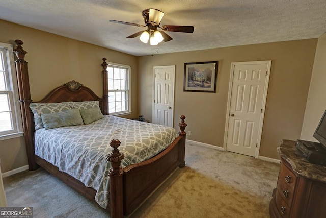 bedroom with baseboards, ceiling fan, a textured ceiling, and light colored carpet