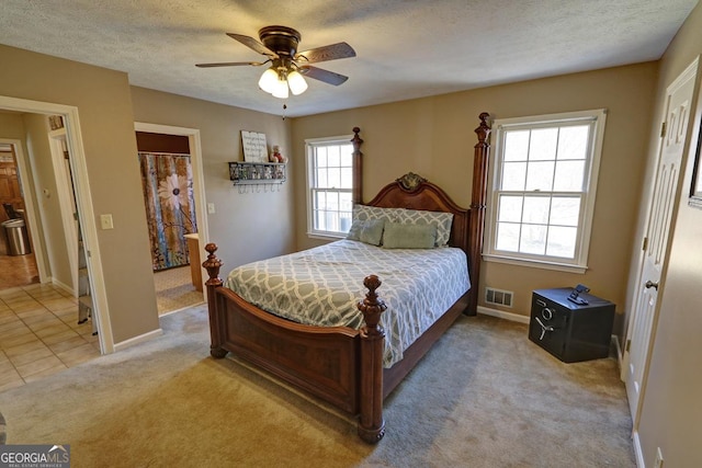 bedroom featuring light tile patterned flooring, visible vents, a textured ceiling, and light colored carpet