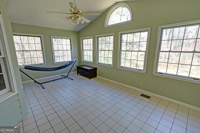 unfurnished sunroom featuring a healthy amount of sunlight, ceiling fan, visible vents, and vaulted ceiling