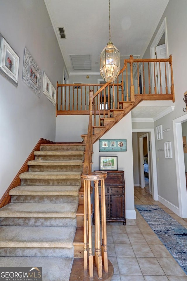 staircase with crown molding, visible vents, a towering ceiling, tile patterned flooring, and baseboards