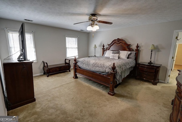 bedroom featuring light carpet, visible vents, and a textured ceiling