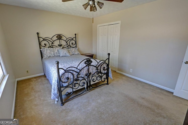 carpeted bedroom with a textured ceiling, ceiling fan, a closet, and baseboards