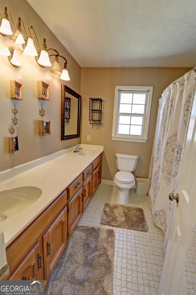 bathroom with double vanity, toilet, tile patterned flooring, a textured ceiling, and a sink