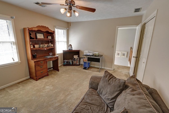 office featuring a ceiling fan, visible vents, light carpet, and baseboards