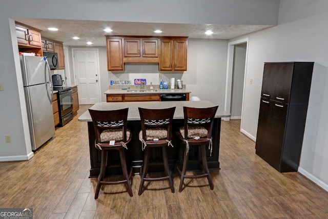 kitchen with black appliances, wood finished floors, a sink, and recessed lighting