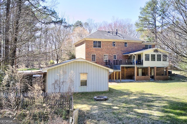 back of property featuring brick siding, a yard, a fire pit, a wooden deck, and stairs