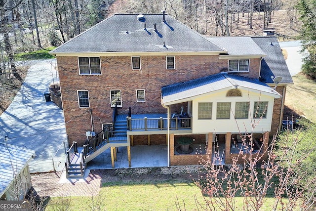 rear view of property featuring a patio area, a chimney, stairway, and brick siding