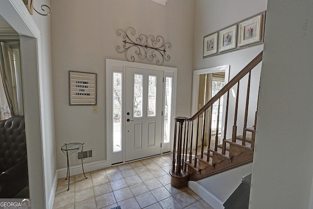 foyer featuring stairs, a high ceiling, baseboards, and light tile patterned flooring