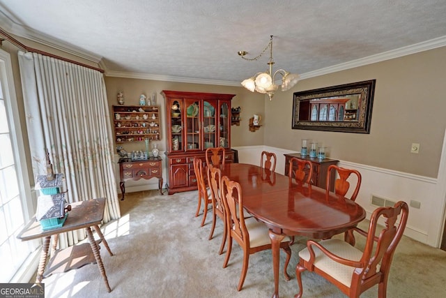 dining area with light carpet, ornamental molding, and an inviting chandelier