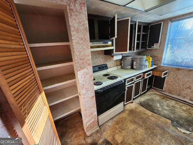 kitchen featuring white electric stove, light countertops, a textured ceiling, dark cabinetry, and under cabinet range hood