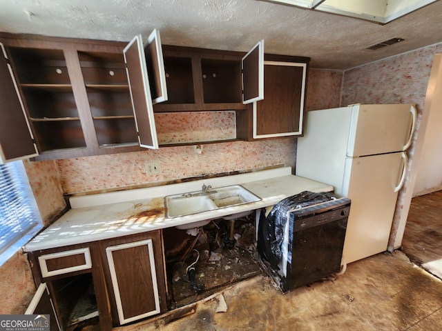 kitchen featuring a textured ceiling, a sink, dark brown cabinets, light countertops, and freestanding refrigerator