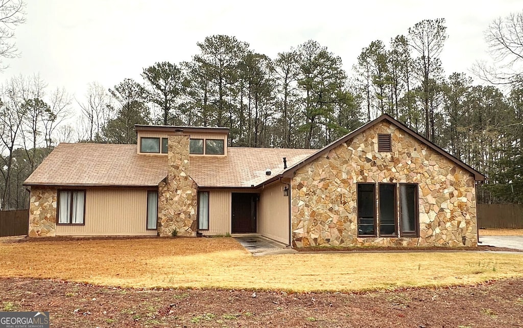 view of front facade featuring stone siding and roof with shingles