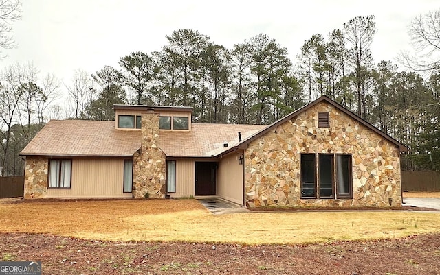 view of front facade featuring stone siding and roof with shingles