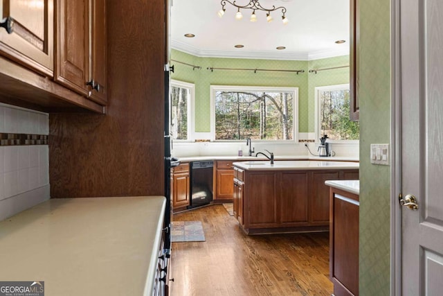 kitchen with brown cabinets, a kitchen island, wood finished floors, light countertops, and dishwasher