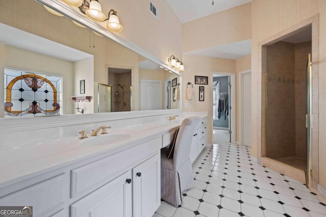 full bath featuring visible vents, wallpapered walls, double vanity, a sink, and a shower stall