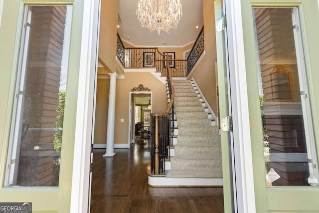 entryway with a chandelier, stairway, wood finished floors, and decorative columns