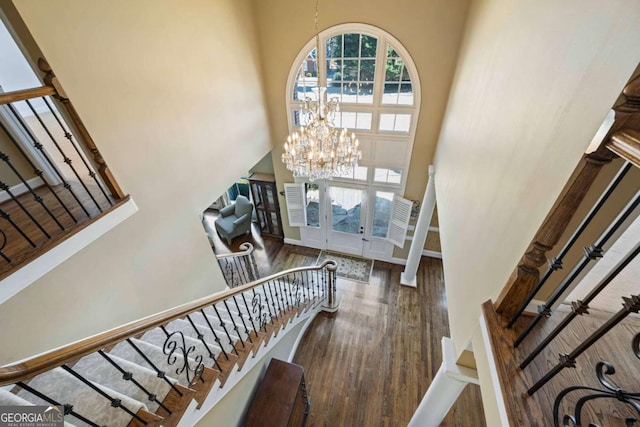 foyer with baseboards, stairway, a high ceiling, an inviting chandelier, and wood finished floors