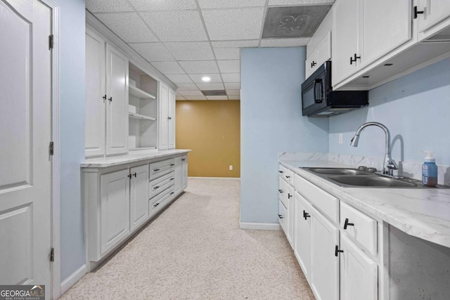 kitchen with baseboards, open shelves, a sink, white cabinets, and light colored carpet