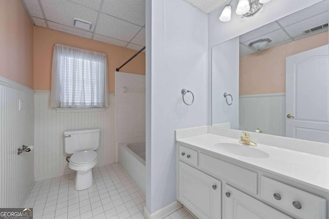 bathroom featuring vanity, a wainscoted wall, visible vents, a paneled ceiling, and toilet