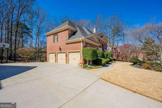 view of side of property featuring fence, driveway, a chimney, a garage, and brick siding