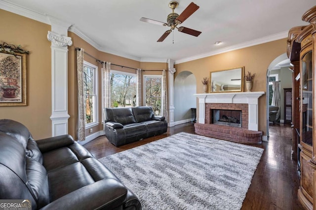 living area featuring baseboards, dark wood finished floors, arched walkways, ceiling fan, and crown molding