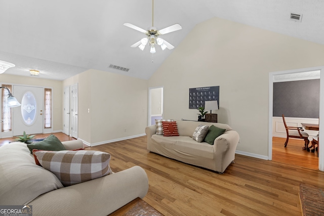 living area featuring high vaulted ceiling, light wood-type flooring, visible vents, and ceiling fan