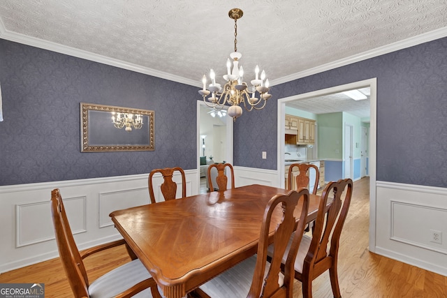 dining area with light wood-style floors, a wainscoted wall, a textured ceiling, and wallpapered walls