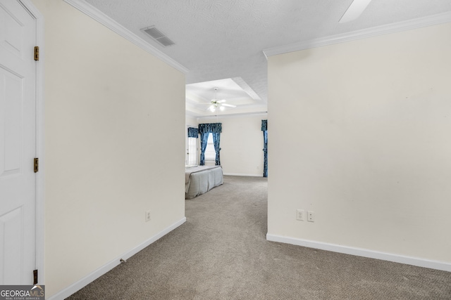 hallway with a textured ceiling, carpet flooring, visible vents, and crown molding