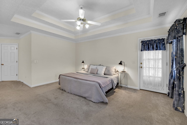 carpeted bedroom featuring ornamental molding, a tray ceiling, visible vents, and baseboards