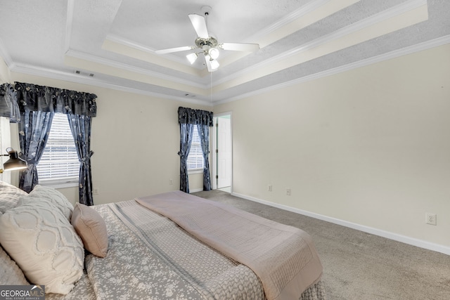 carpeted bedroom featuring baseboards, visible vents, a tray ceiling, and crown molding