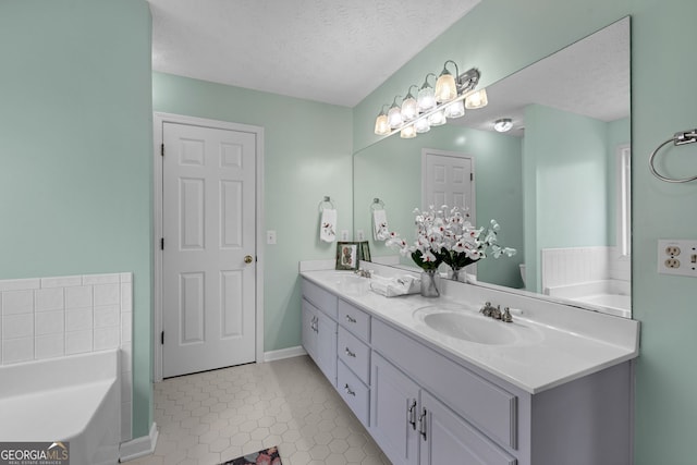 bathroom with a sink, a garden tub, double vanity, and a textured ceiling