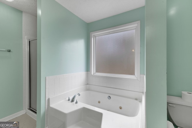 bathroom featuring a jetted tub, a stall shower, toilet, and a textured ceiling