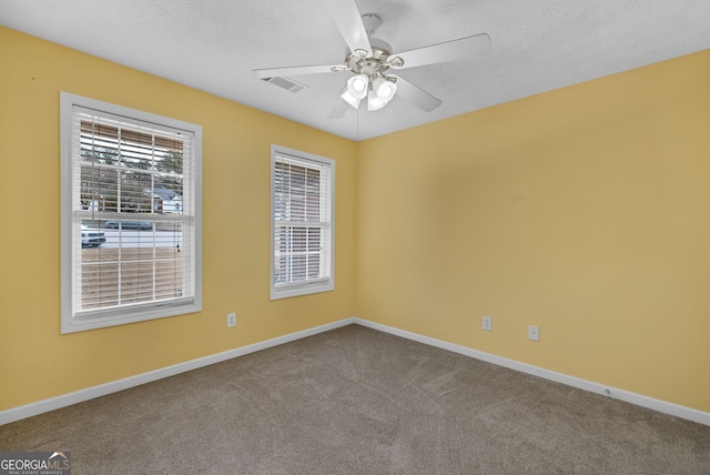 carpeted empty room with ceiling fan, a textured ceiling, visible vents, and baseboards