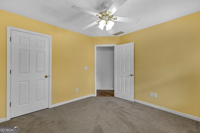 unfurnished bedroom with carpet, visible vents, ceiling fan, a textured ceiling, and baseboards