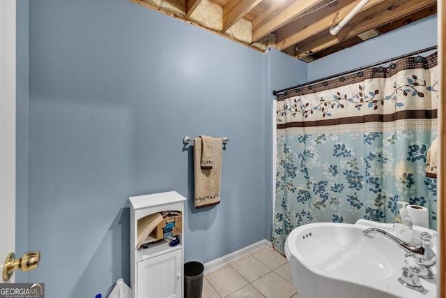 full bath featuring curtained shower, tile patterned flooring, baseboards, and a sink