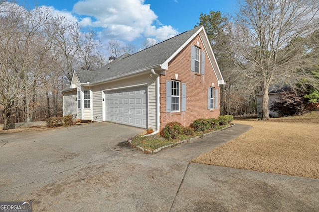 view of home's exterior with a garage, driveway, brick siding, and roof with shingles