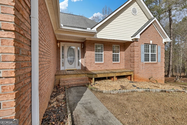 property entrance featuring brick siding and roof with shingles