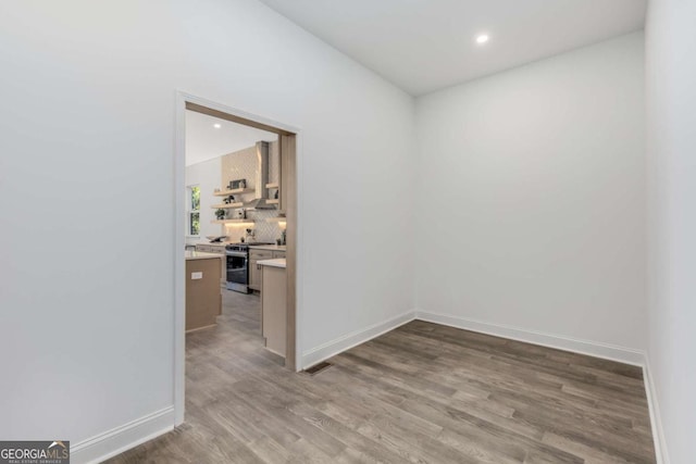 spare room featuring baseboards, wood finished floors, and recessed lighting