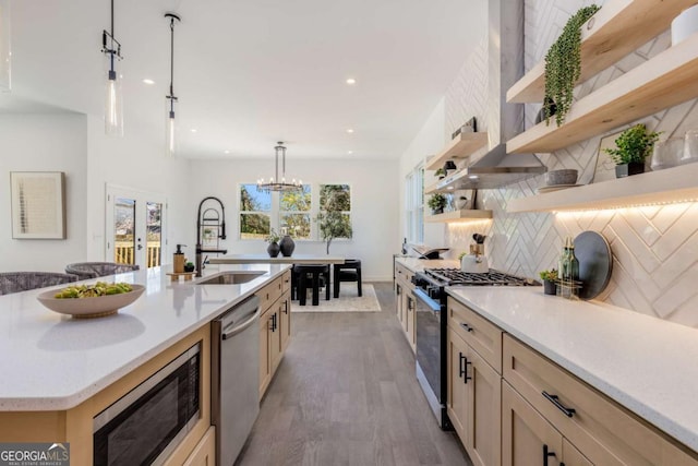 kitchen featuring stainless steel appliances, french doors, open shelves, tasteful backsplash, and a large island with sink