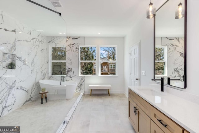 full bath with visible vents, a wealth of natural light, a freestanding tub, and vanity